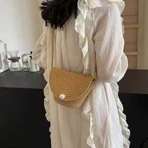 Handmade khaki straw bucket bag with a large pearl buckle and a slim shoulder strap