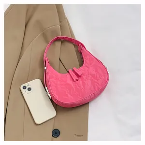 Macro detail van een glanzende roze hobo tas in maanvorm met geplooide leertextuur