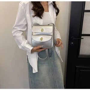 Detail van een zilveren metallic leren handtas met dubbele gouden draaisluitingen