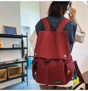 Detail view of burgundy waterproof backpack with flap closure and silver magnetic snaps