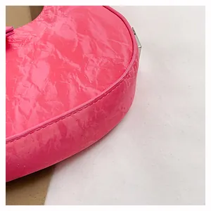 Detail van fuchsia roze handtas van rimpelig lakleer met zilveren metalen accenten
