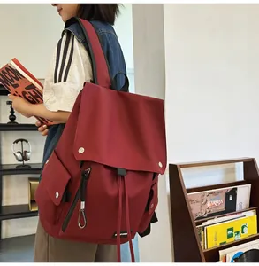 Side view of a vintage burgundy backpack with flap closure and drawstring detail