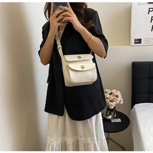 Detail van crème witte crossbodytas met dubbele compartimenten en gouden metalen sluitingen