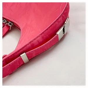 Detailopname van glanzend magenta lakleer textuur en zilveren gesp van de schoudertas