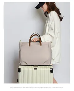 Beige laptoptas met leren handvatten bevestigd aan de trekstang van een koffer