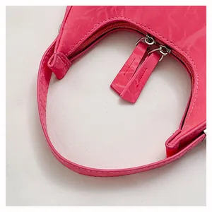 Detail van de fuchsia lakkleren handtas met dubbele zilveren ritsen en y2k-stijl