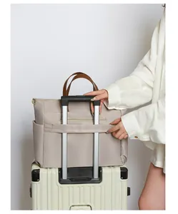 Detail van beige laptoptas met bagageriem en zijvakken bevestigd aan een koffer