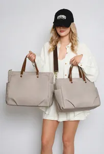 Detail of light beige nylon laptop tote with brown leather handles and adjustable strap