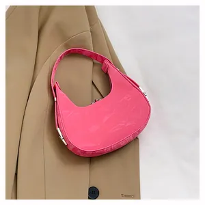 Detail van een felroze lakschoudertas op een kaki blazer in een stijlvolle setting
