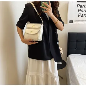 Chique crèmekleurige vierkante crossbodytas gedragen door een model in een moderne setting