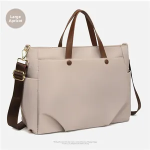 Detail view of apricot laptop tote bag with brown leather handles and gold hardware