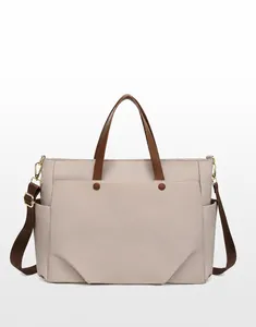 Front view of beige waterproof laptop tote bag with brown handles and shoulder strap