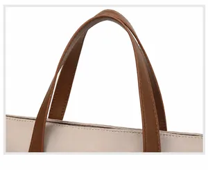 Close-up of brown faux leather handles and stitching on large laptop tote bag