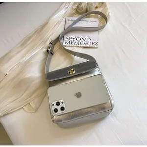 Detail van een zilveren crossbodytas met telefoon om de grootte en inhoud te tonen