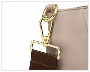 Detail of detachable gold metal swivel hook and brown woven strap on laptop bag