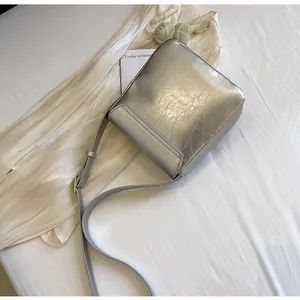 Detail van de zilveren vierkante crossbodytas met metallic kreukeltextuur en riem