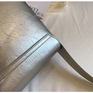 Close-up van zilveren crossbodytas met metallic kreuktextuur en fijne stikseldetails