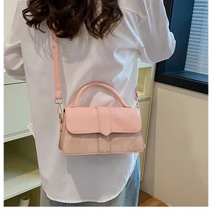 Detail van lichtroze crossbodytas met gouden hardware en gemengde texturen op een model