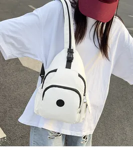 Close-up of white nylon crossbody bag with black zippers and adjustable straps on model