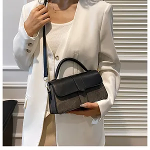 Detail van een tweekleurige crossbodytas met zwarte leren flap en grijze suède textuur