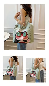 Detail of light green canvas tote bag featuring quirky cartoon girl and lucky text