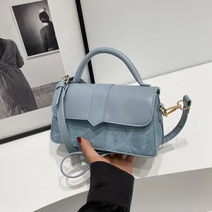 Detail van lichtblauwe crossbodytas met denimtextuur en gouden hardware accenten