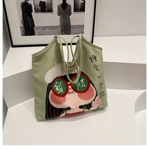 Detail of light green canvas tote bag featuring a cartoon girl illustration and vertical text