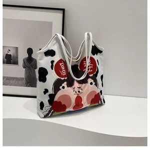 Close-up of canvas tote bag featuring cow print and cartoon character with Chinese characters