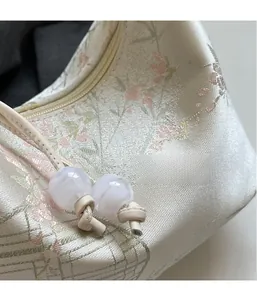 Close-up of embroidered floral jacquard fabric texture and decorative beads on handbag