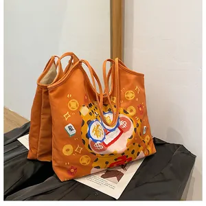 Detail of orange canvas tote bag with festive cartoon lion and Chinese luck symbols