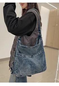 Detail van een gewassen blauwe denim tote bag met zijzakken en een verstelbare schouderband