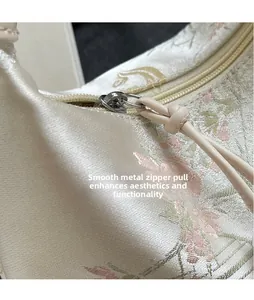 Detail of smooth polished hardware puller and floral embroidery on the silk bag