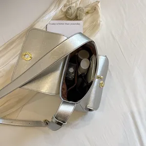 Zilveren crossbodytas met textuur en gouden slot toont de binnenkant van de tas