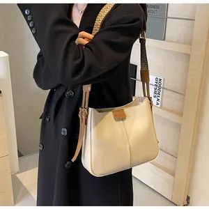 Detail van minimalistische beige schoudertas met gedessineerde brede riem en leren label