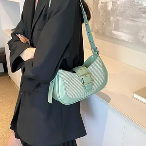Detail of light green woven underarm bag featuring a stylish metal buckle strap