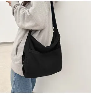 Zijaanzicht van een grote zwarte canvas draagtas met verstelbare riem in een modern interieur