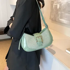 Detail of light green underarm bag featuring woven panel and leather buckle closure