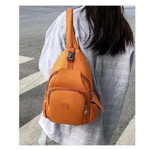 Detail of bright orange nylon crossbody chest bag with multiple zipper compartments