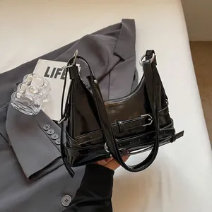 Stijlvolle zwarte laklederen bucketbag met zilveren hardware op een neutrale achtergrond