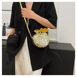Dettaglio della borsa a tracolla a forma di mela con paillettes dorate e chiusura foglia
