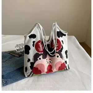Close-up of canvas tote bag with cow print and artistic cartoon girl illustration