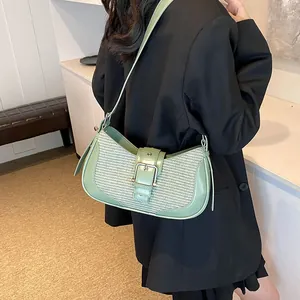 Detail of light green woven underarm bag with silver buckle and leather strap on model