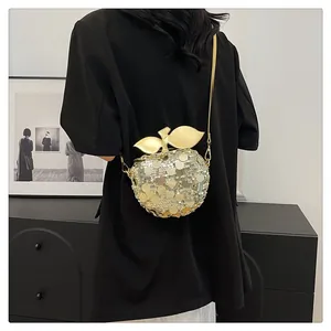 Dettaglio della borsa a tracolla creativa a forma di mela con paillettes dorate e foglie