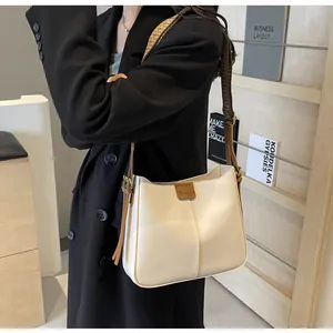 Detail van gebroken witte draagtas met brede geometrische riem en bruine franje