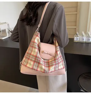 Detail der rosa karierten Hobo-Tasche mit dekorativer Schleife und Lederbesatz am Modell