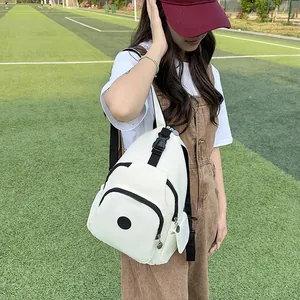 White nylon backpack for women with multiple pockets shown on a model at a sports field
