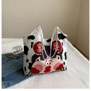Close-up of white canvas tote bag featuring cow print and cute cartoon girl graphic