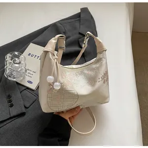 Detailed embroidery on cream satin shoulder bag with floral patterns and pearl charms