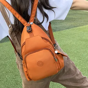 Orange nylon multi-functional backpack with sport logo on a green grass background