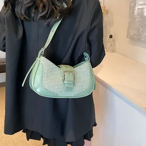 Detail of mint green leather and woven fabric shoulder bag worn by model in black suit